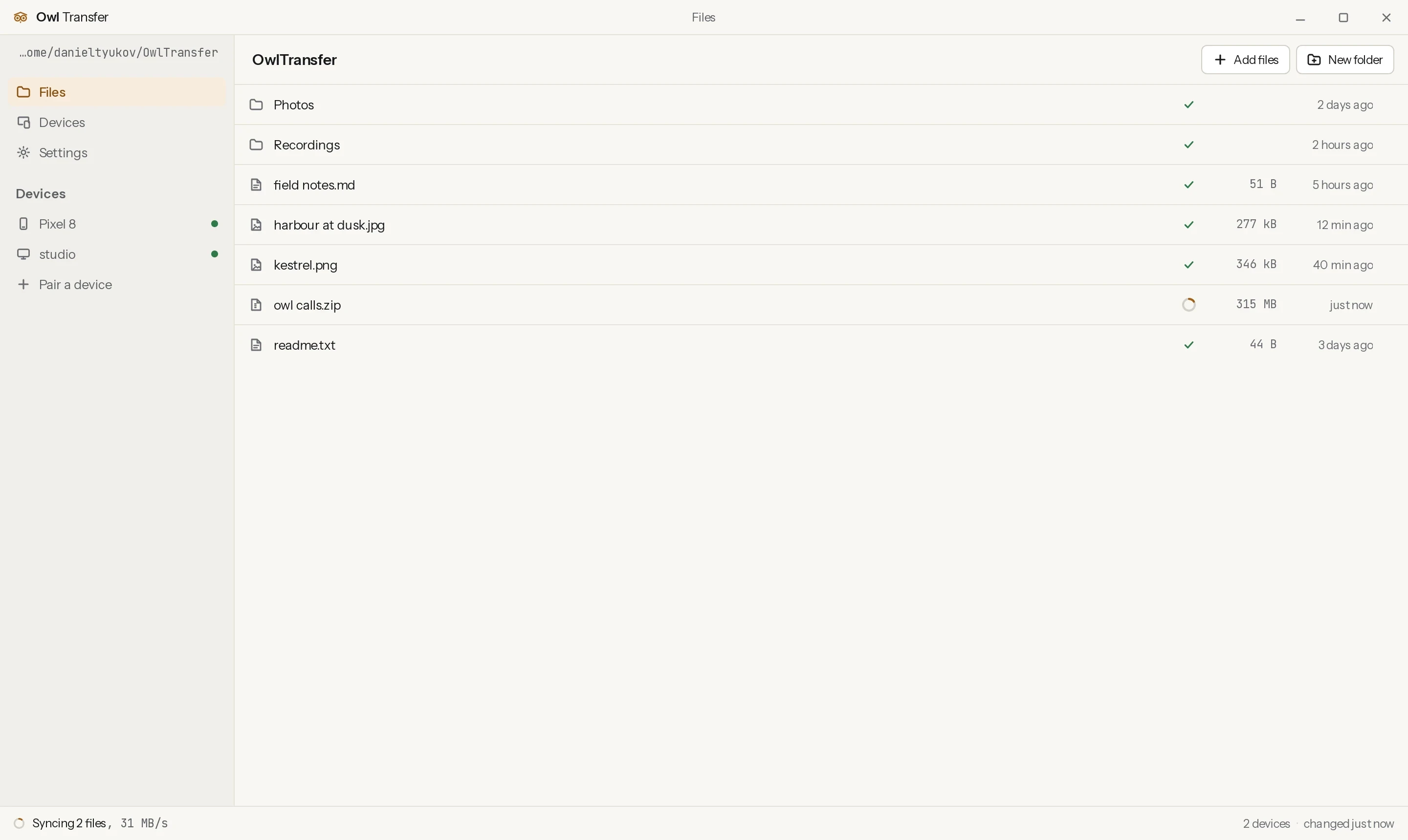 The OwlTransfer desktop app with the sync folder and two paired devices in the sidebar, a file list with a sync badge on every entry, and one file part way through