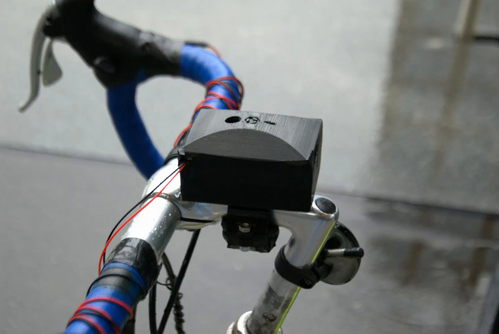 Close three-quarter view of the black 3D-printed case mounted above the handlebar stem