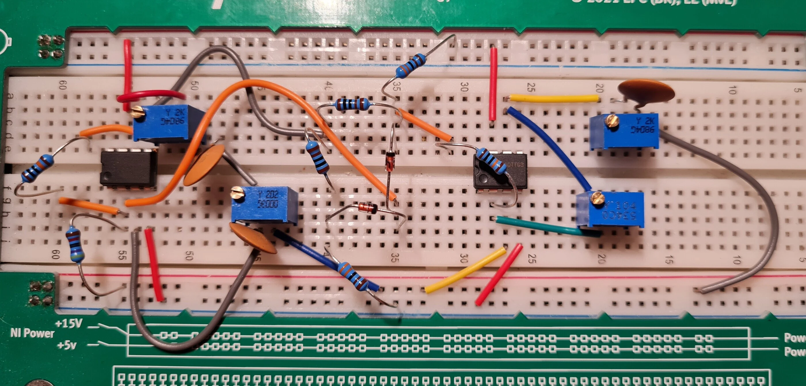 The Wien-bridge oscillator on an NI ELVIS breadboard: two op-amps, blue trimmers, ceramic capacitors and a diode pair